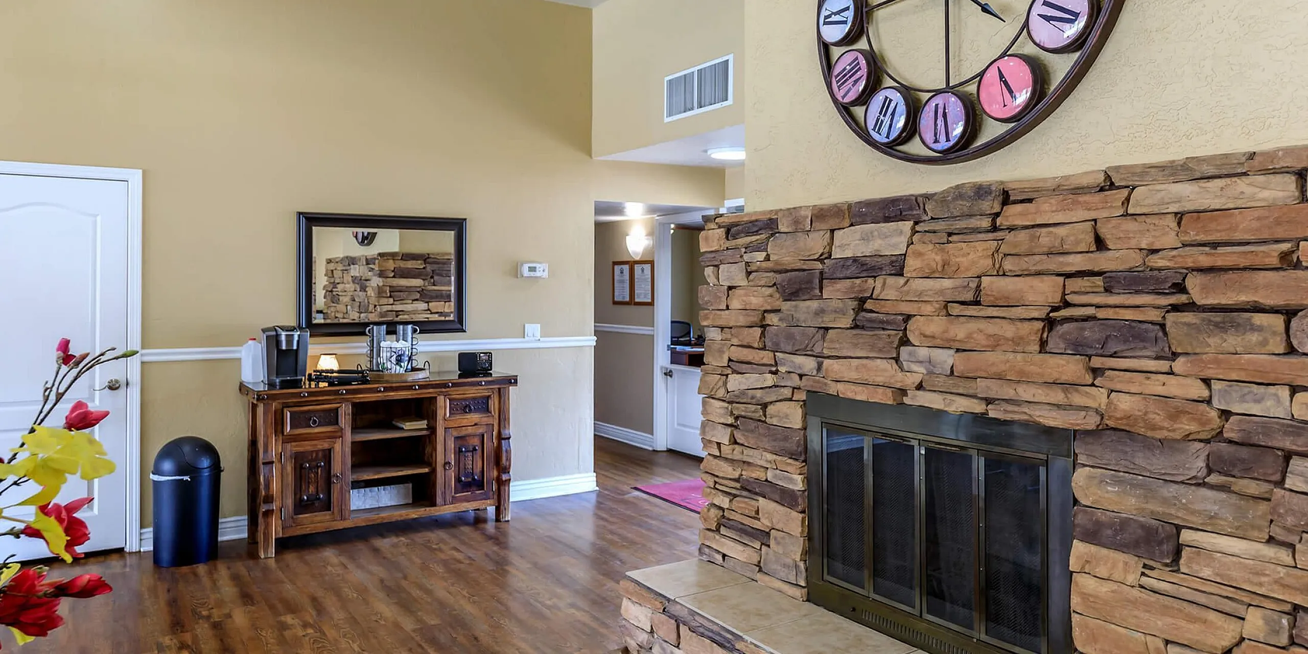 Inviting living room featuring a rustic stone fireplace, elegant wooden floors, and a charming wall clock, perfect for cozy gatherings.