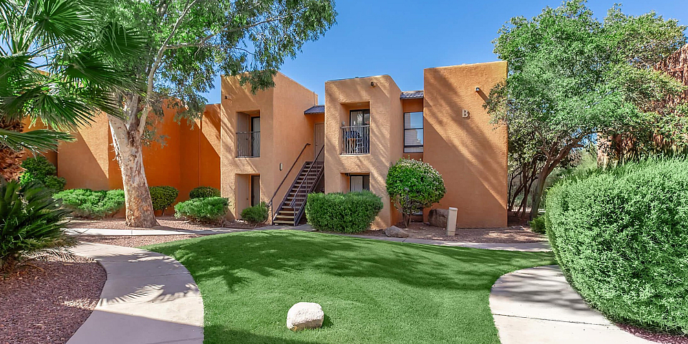 Charming apartment complex with warm terracotta exteriors, surrounded by lush greenery and scenic pathways.