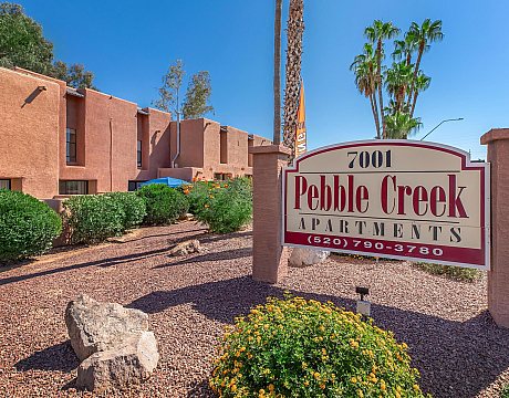 Charming Pebble Creek Apartments with inviting desert landscaping and vibrant palm trees, perfect for Arizona living.