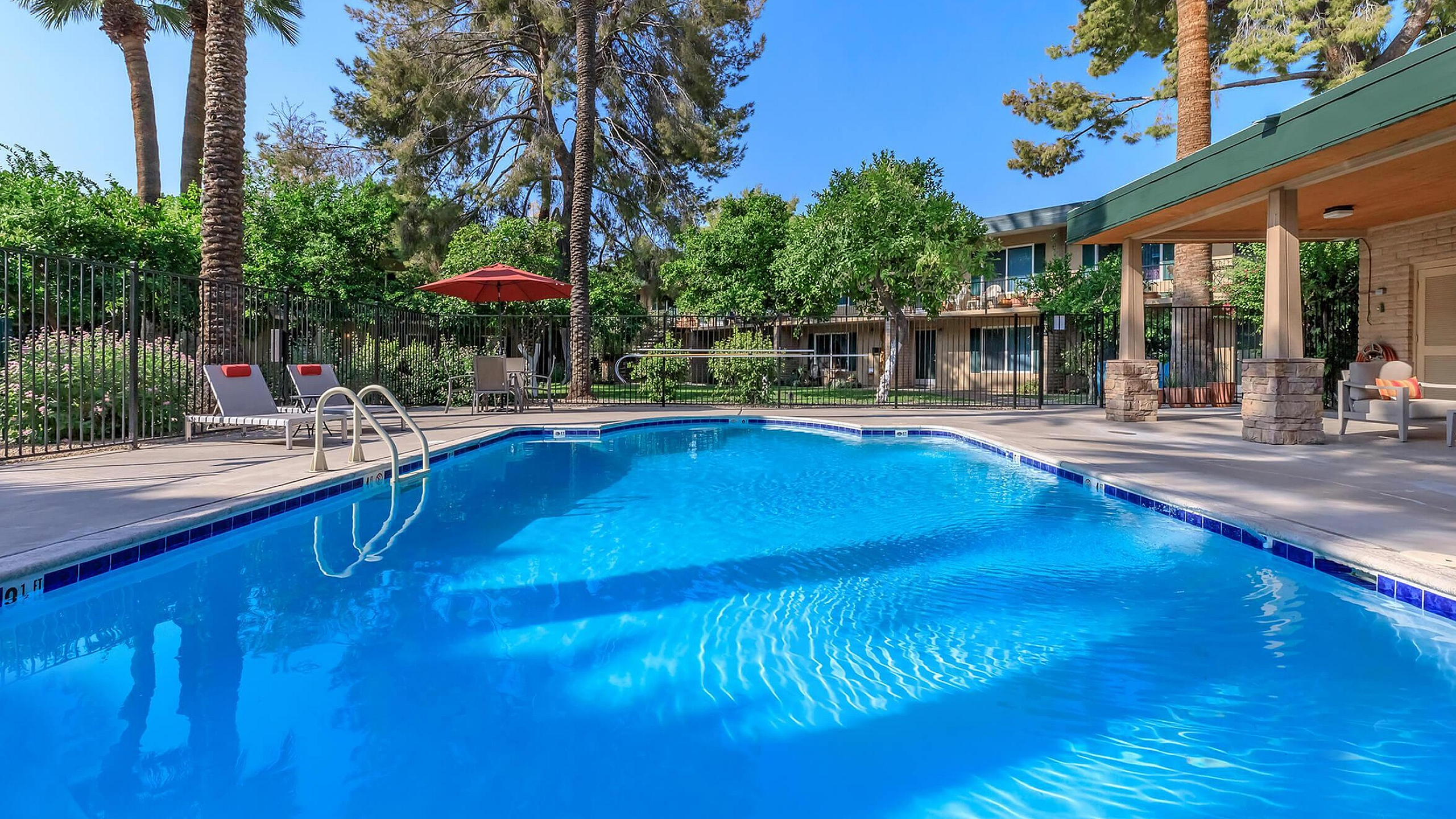 Inviting outdoor pool area with crystal-clear water, surrounded by lush greenery and comfortable loungers, creating a perfect oasis for relaxation.