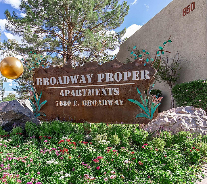 Welcome to Broadway Proper Apartments, nestled in lush greenery with vibrant flowers, offering serene living at 7680 E. Broadway.