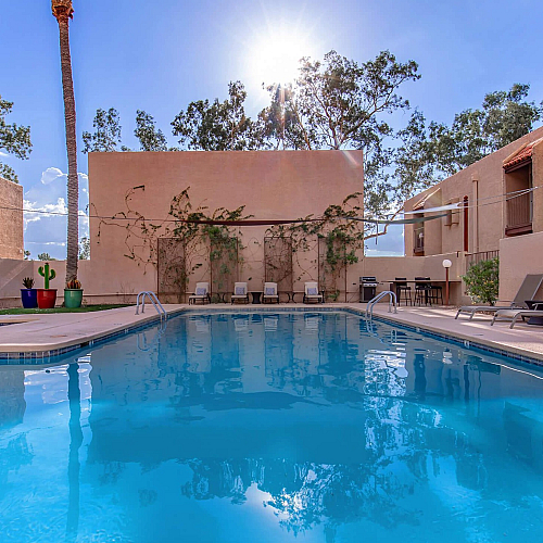 Inviting outdoor pool area with modern sun loungers, surrounded by palm trees and lush greenery, perfect for relaxation and leisure.