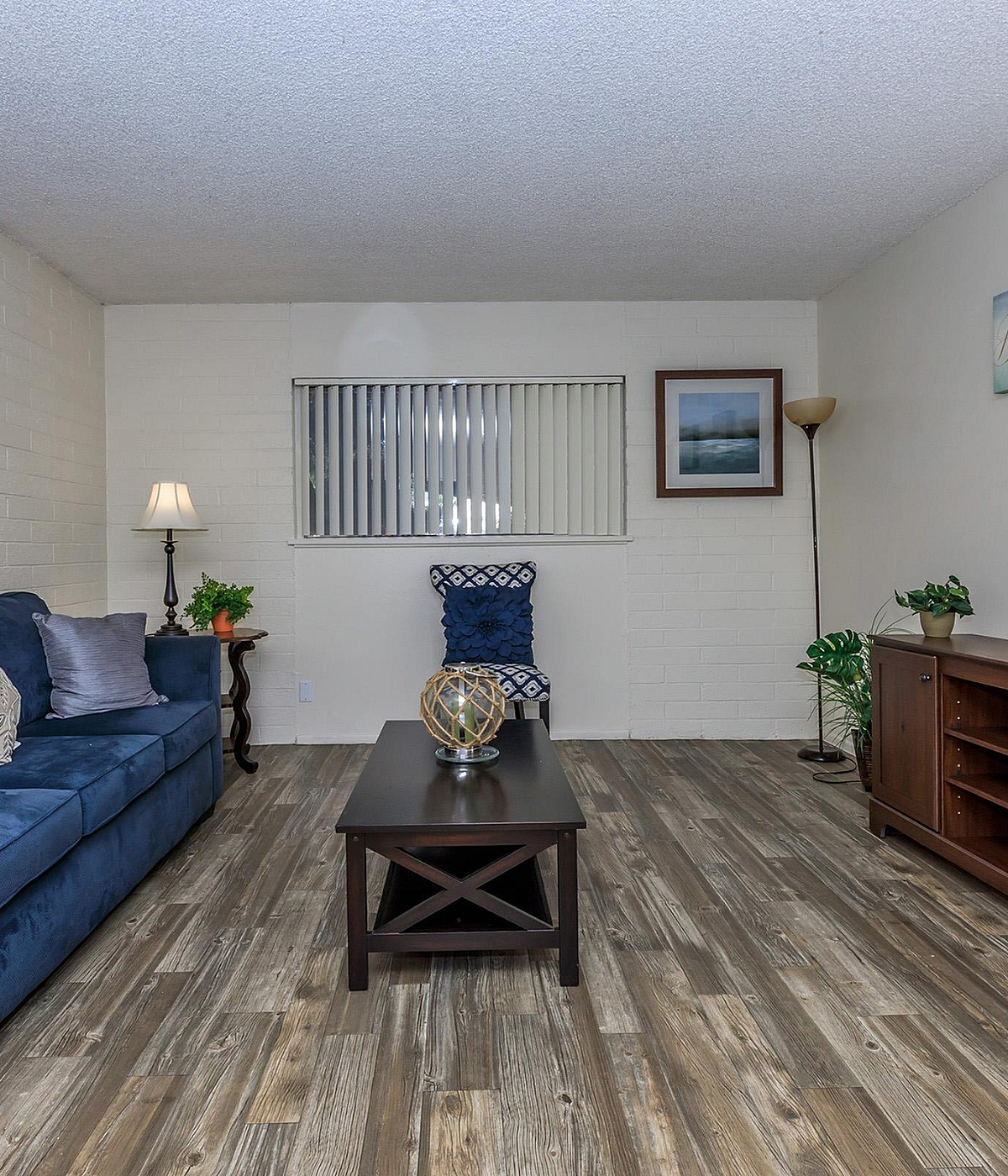 Inviting living room with a plush blue sofa, chic decor, and stylish wooden flooring, perfect for relaxation and entertaining.