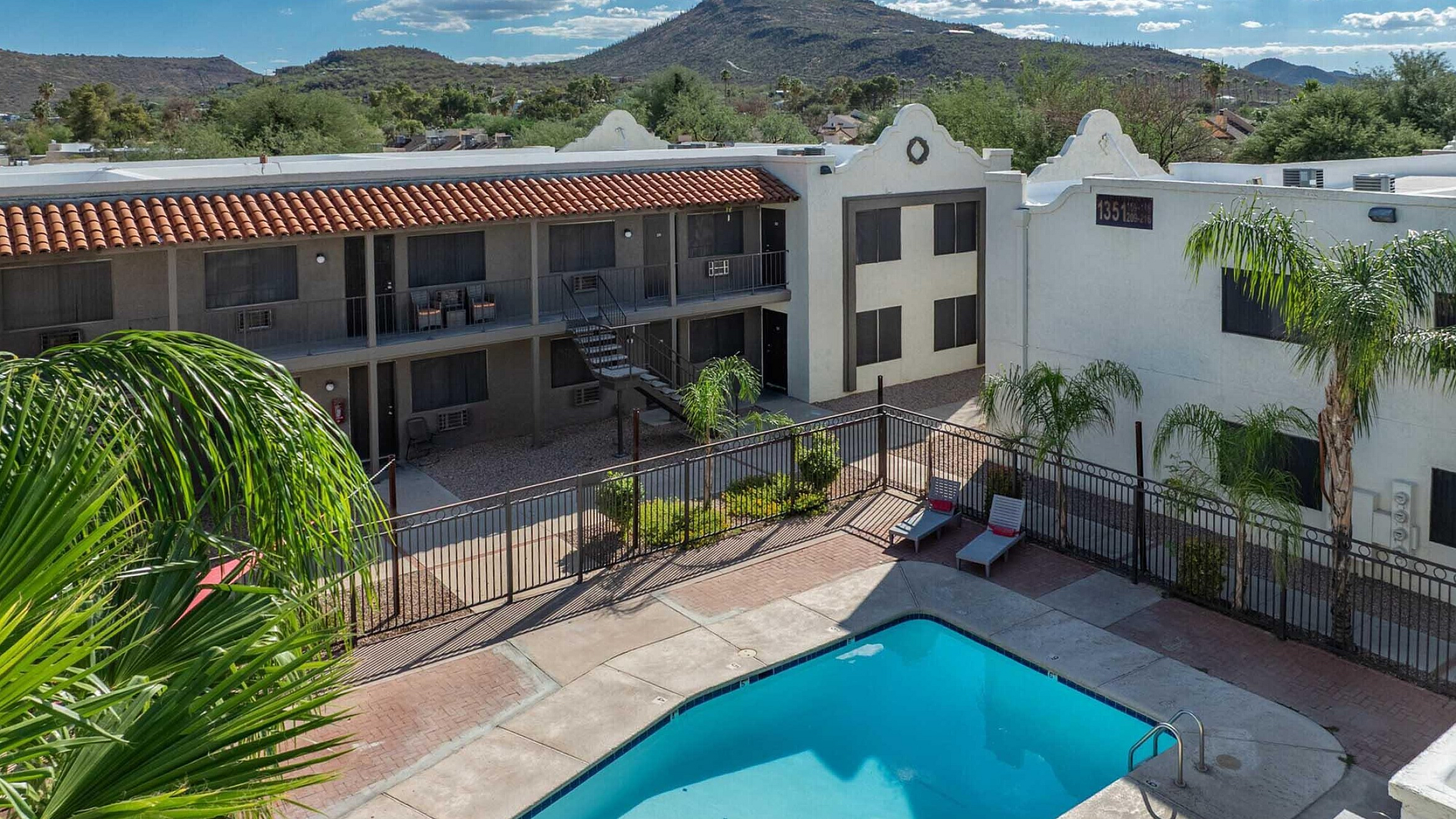 Charming apartment complex with a sparkling outdoor pool, surrounded by lush greenery and stunning mountain views.