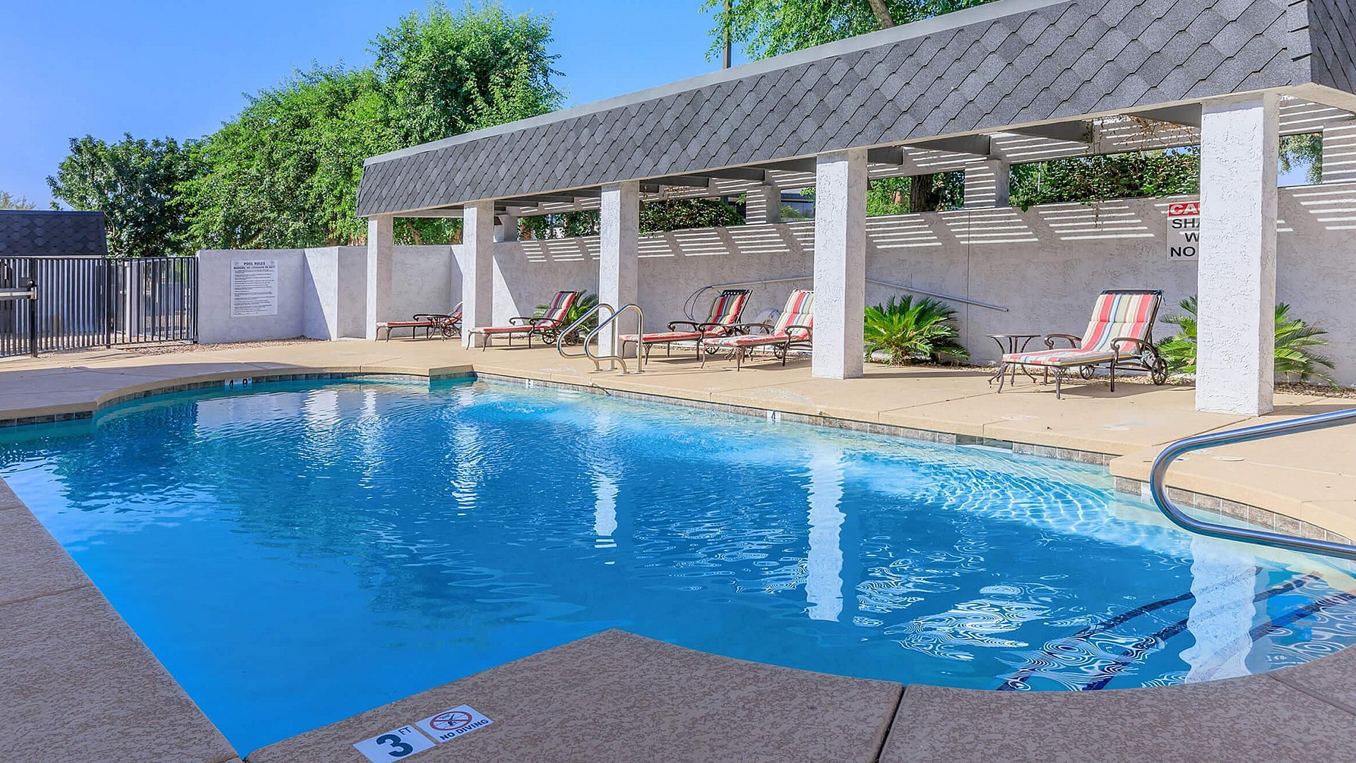 Inviting outdoor pool area with sun loungers, surrounded by lush greenery and modern pergola.