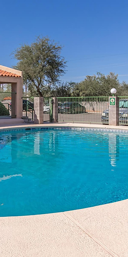 Inviting outdoor pool area with sun loungers and shaded seating, perfect for relaxation under clear blue skies.
