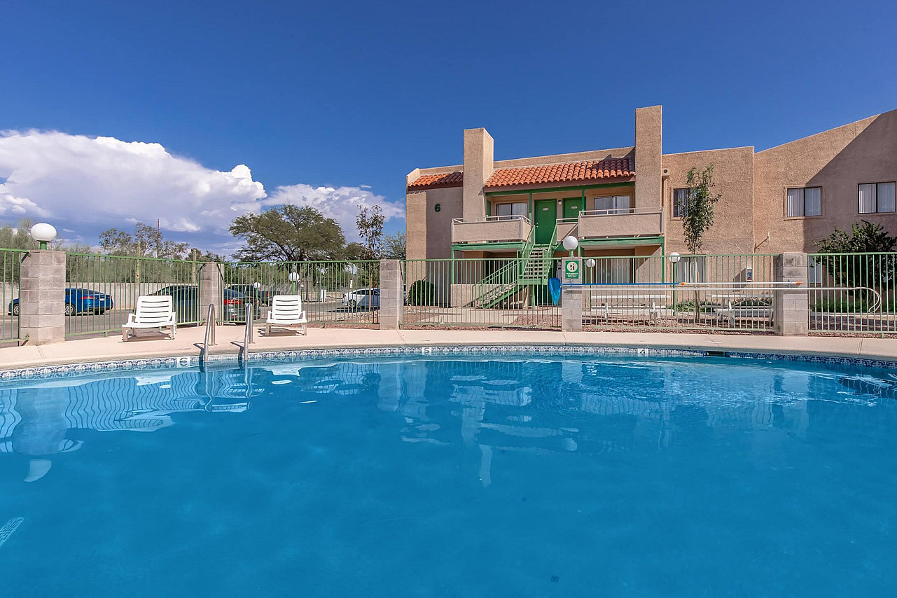 Inviting apartment complex with a refreshing swimming pool under a clear blue sky, offering a relaxing outdoor oasis.