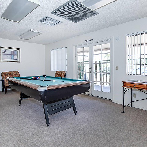 Bright and inviting game room featuring a pool table, cozy seating, and elegant French doors.