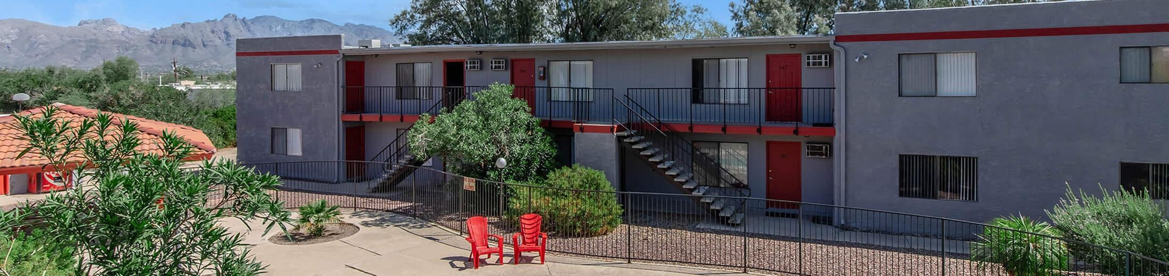 Inviting apartment complex with a sparkling pool, surrounded by lush greenery and scenic mountain views, offering comfortable living spaces in a serene environment.