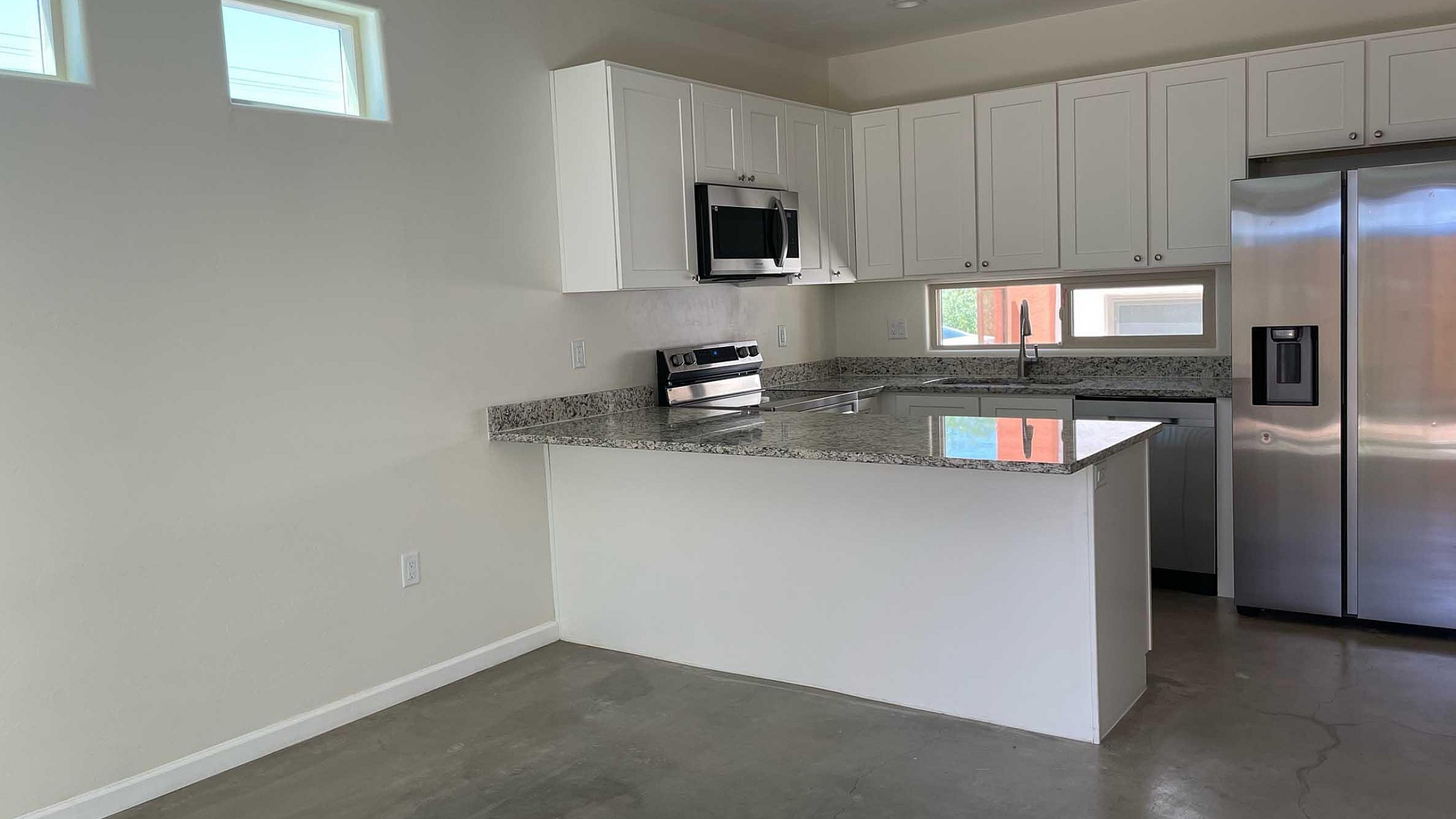 Modern kitchen with sleek granite countertops, stainless steel appliances, and ample cabinet space, ideal for stylish living.