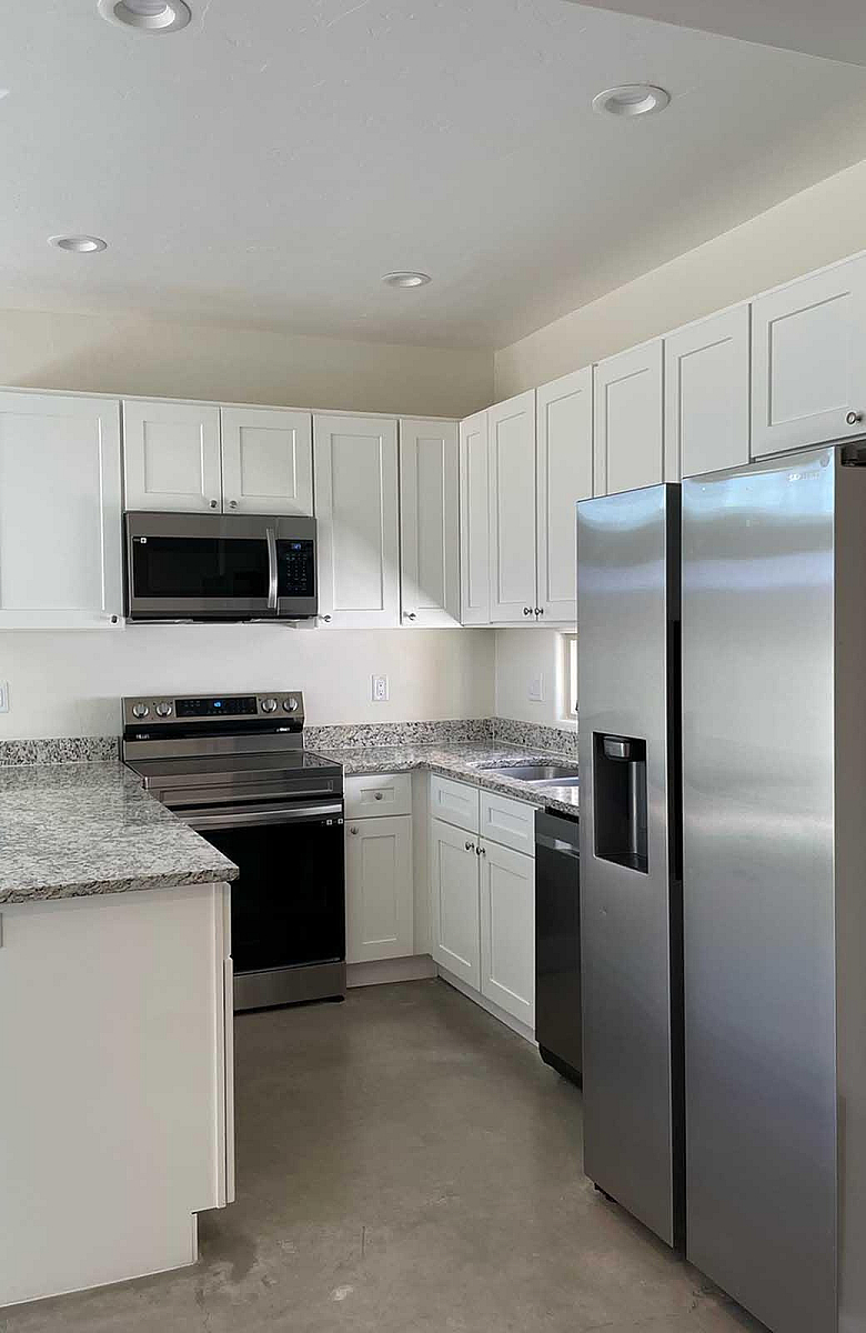 Modern kitchen featuring sleek stainless steel appliances, elegant white cabinetry, and stylish granite countertops.