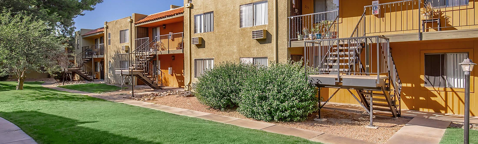 Charming apartment exterior with vibrant colors, lush green lawns, and a serene pathway, ideal for modern living.