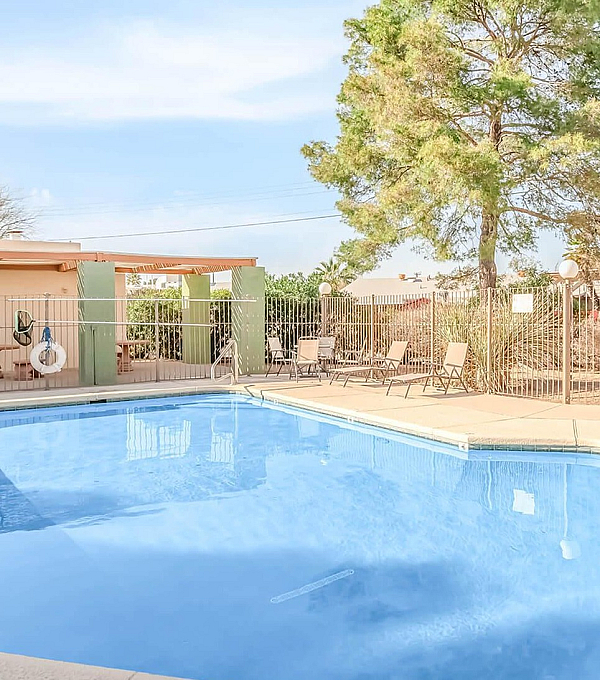 Inviting outdoor pool area with lounge chairs and lush greenery, ideal for relaxing and soaking up the sun.