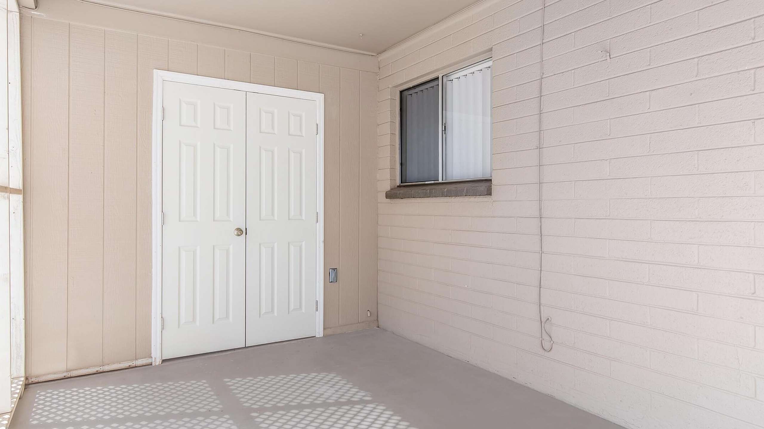 Bright, inviting enclosed patio space with modern white double doors and decorative brick walls.