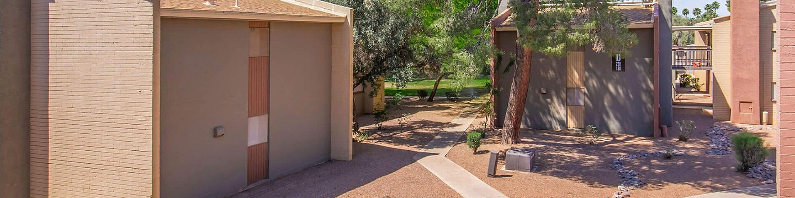 Charming apartment complex with modern architecture, surrounded by lush trees and serene landscaping.