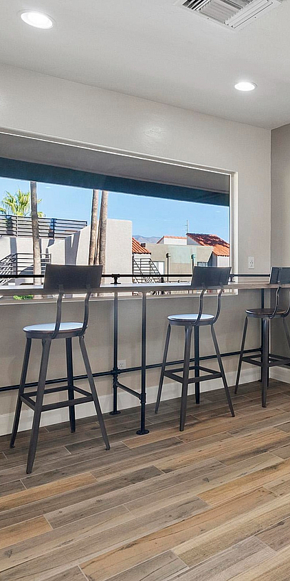 Inviting modern dining area with sleek bar stools and large windows showcasing a vibrant outdoor view.