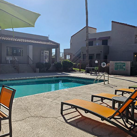Inviting apartment complex pool with stylish loungers and shaded seating, perfect for relaxation under the sun.
