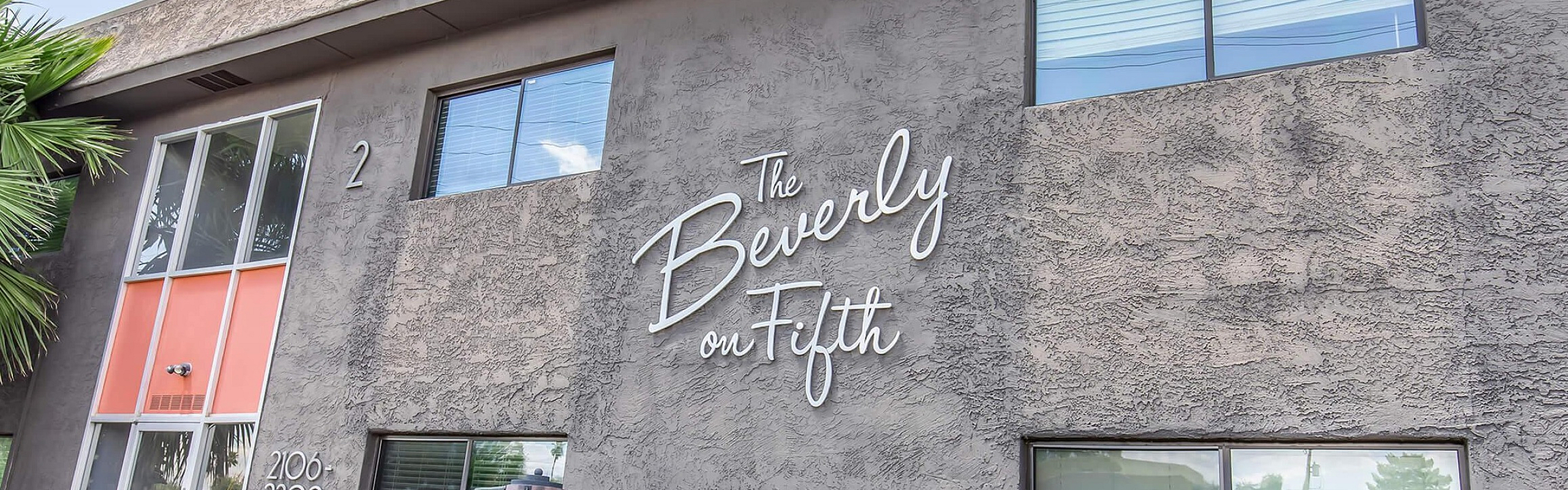Modern apartment building with stylish signage and lush greenery at The Beverly on Fifth.