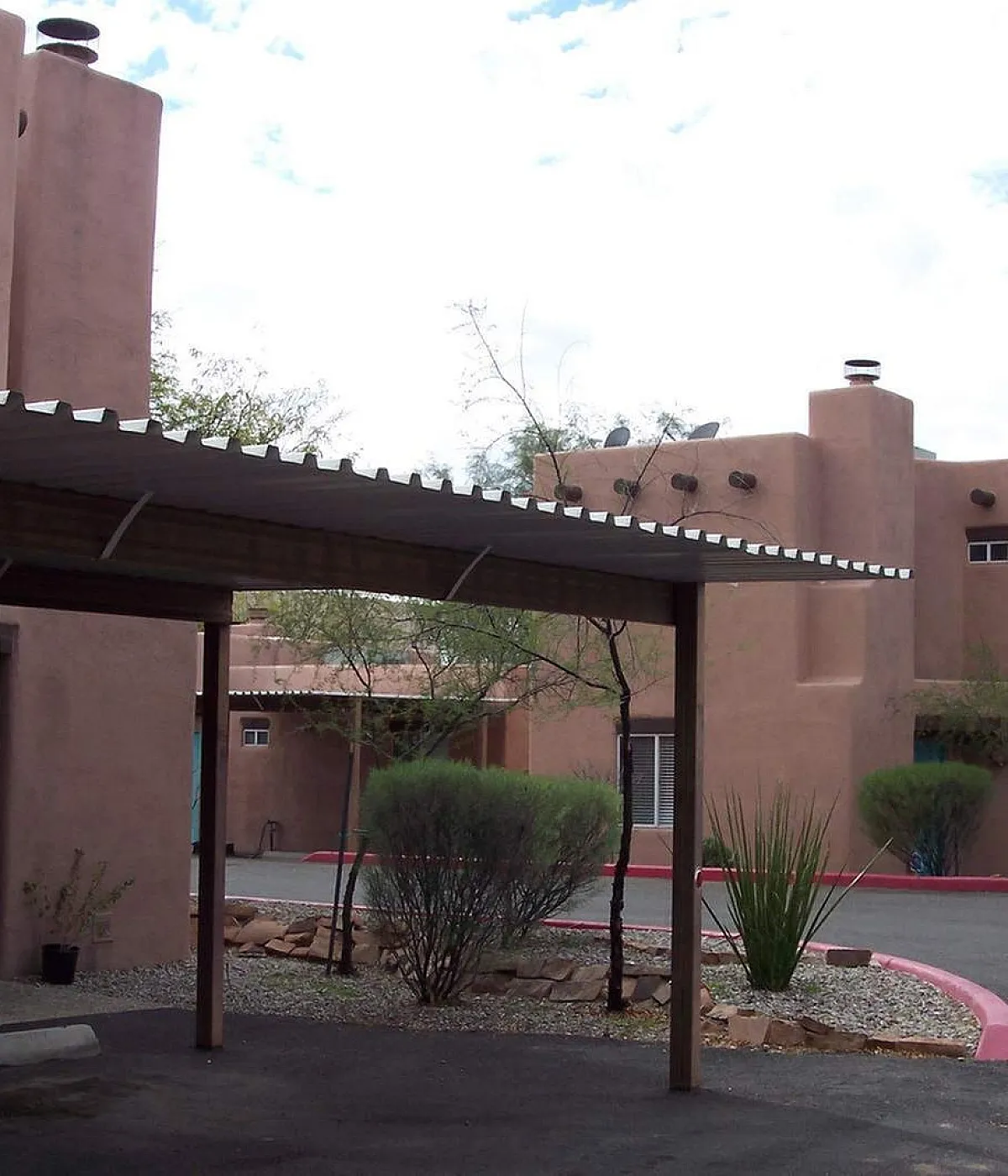 Inviting adobe-style apartment complex with charming arched windows, nestled in a serene desert landscape.