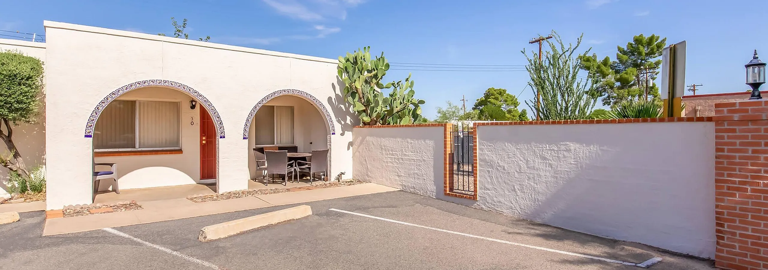 Charming villa with distinctive arch design, cozy outdoor seating, and vibrant desert landscaping.