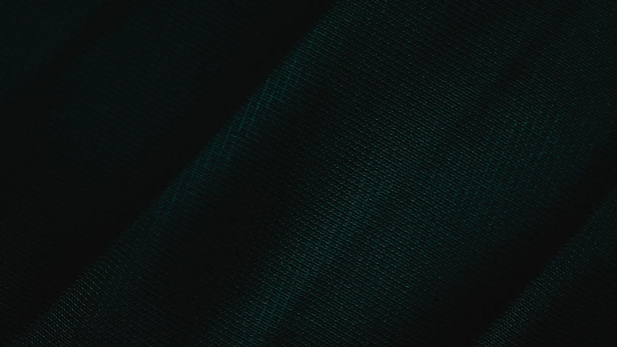 Elegant close-up of dark green textured fabric, showcasing its rich color and fine weave.