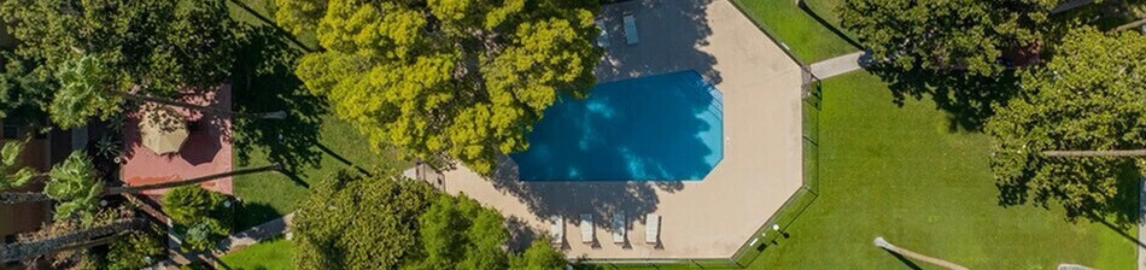 Stunning aerial view of a lush garden complex with a sparkling pool surrounded by vibrant greenery and inviting walkways.