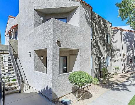 Modern apartment exterior showcasing clean architectural lines, light gray facade, and scenic surroundings with lush greenery.