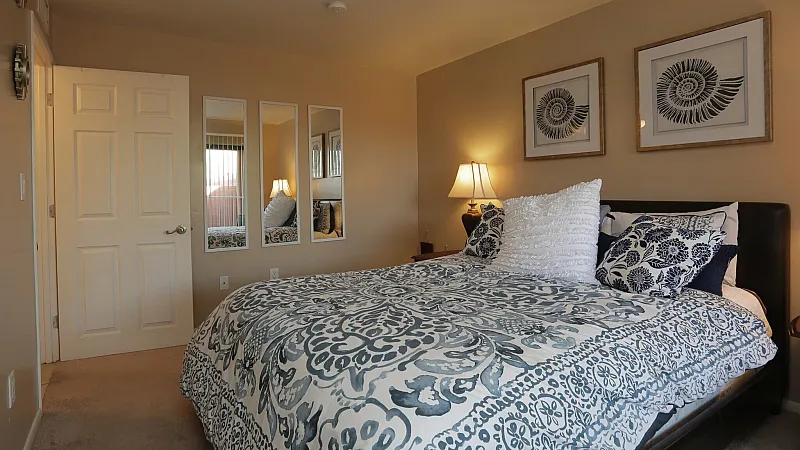 `Bedroom with patterned bedding, soft lighting, and modern decor at San Simeon Apartments in Tucson, AZ`