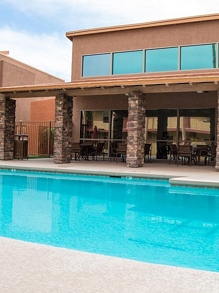 Inviting outdoor pool area with modern shaded seating and elegant stone-columned architecture.