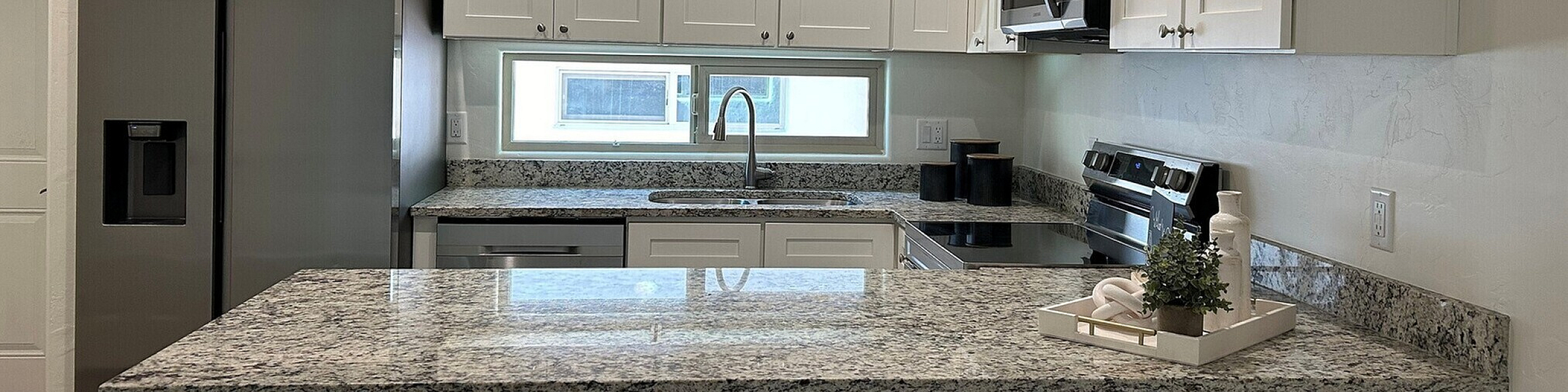 Modern kitchen with sleek stainless steel appliances, elegant granite countertops, and stylish white cabinetry.