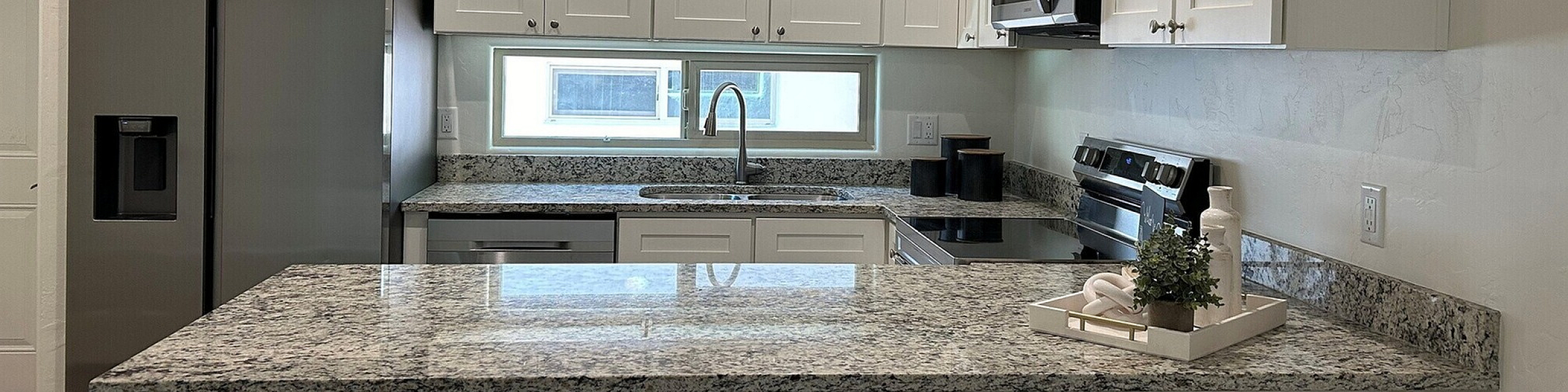 Sleek modern kitchen with stainless steel appliances, elegant granite countertops, and crisp white cabinetry, offering a bright and inviting cooking space.