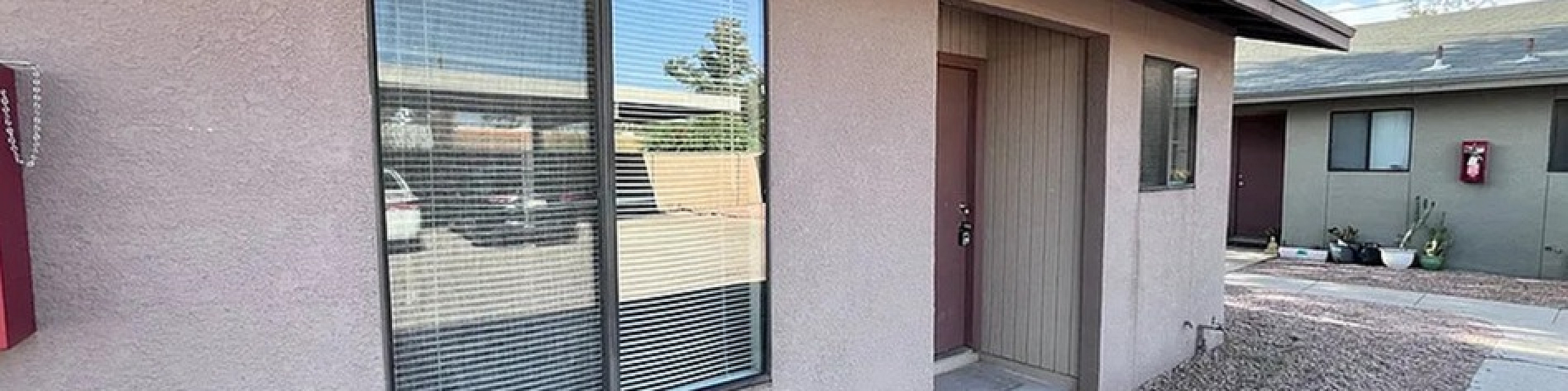 Charming single-story apartment with modern design, featuring large front windows and a private entryway with a desert landscape.