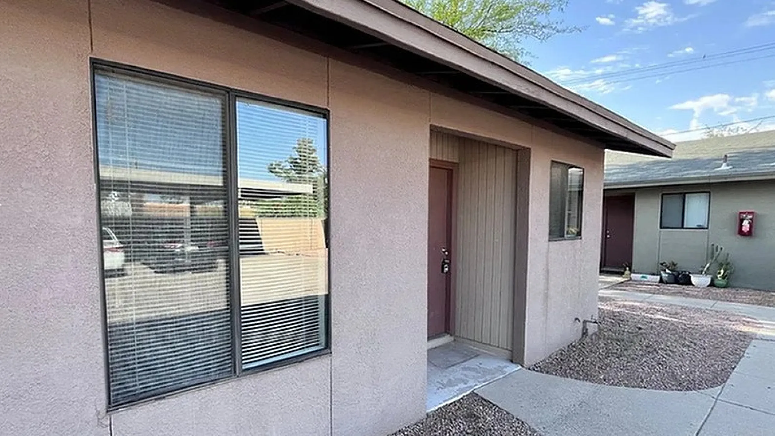 Charming apartment exterior with modern windows, a welcoming entrance, and well-maintained pathway in a peaceful neighborhood setting.