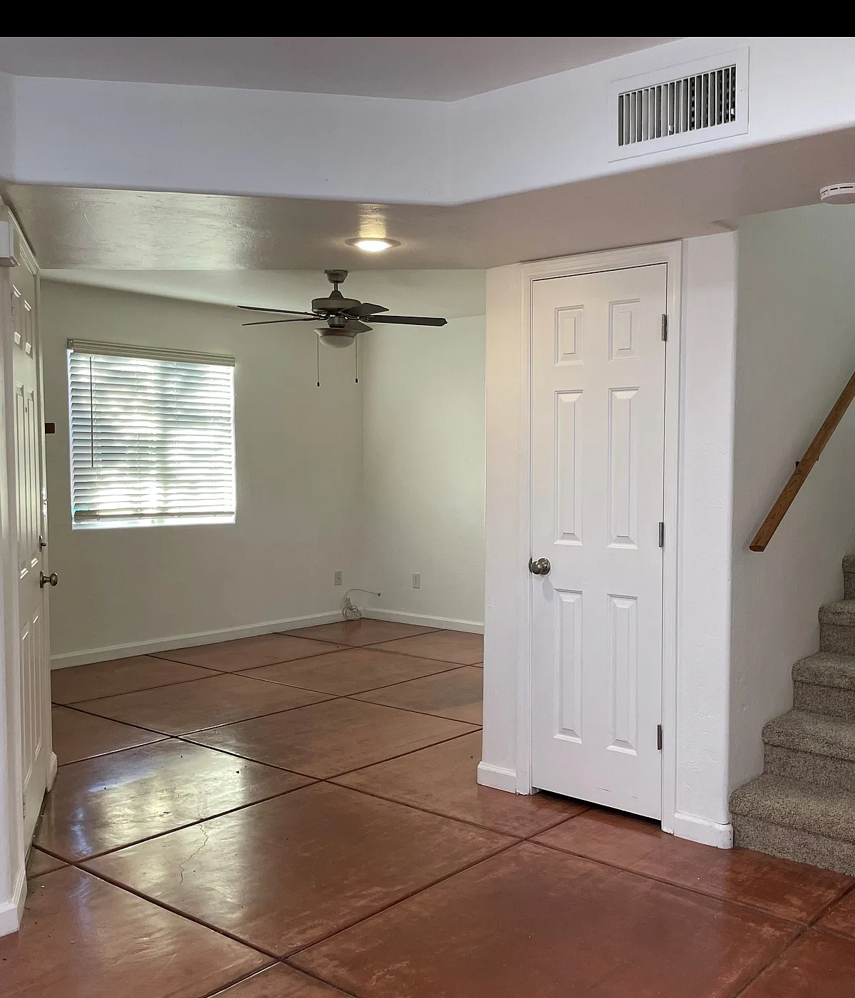 Bright and inviting interior with sleek tile flooring, cozy carpeted stairs, and a ceiling fan, offering a perfect blend of comfort and style.