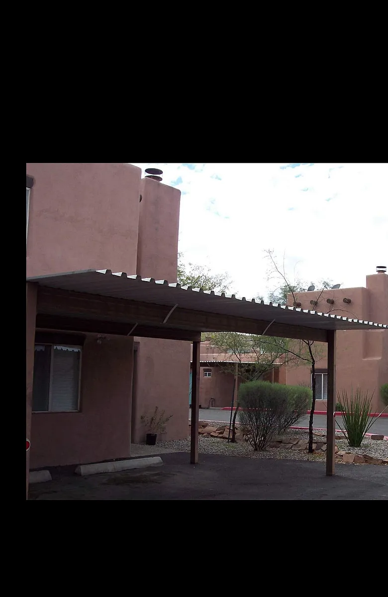 Charming adobe-style apartment complex with landscaped greenery and modern carport, capturing Southwest architectural elegance.