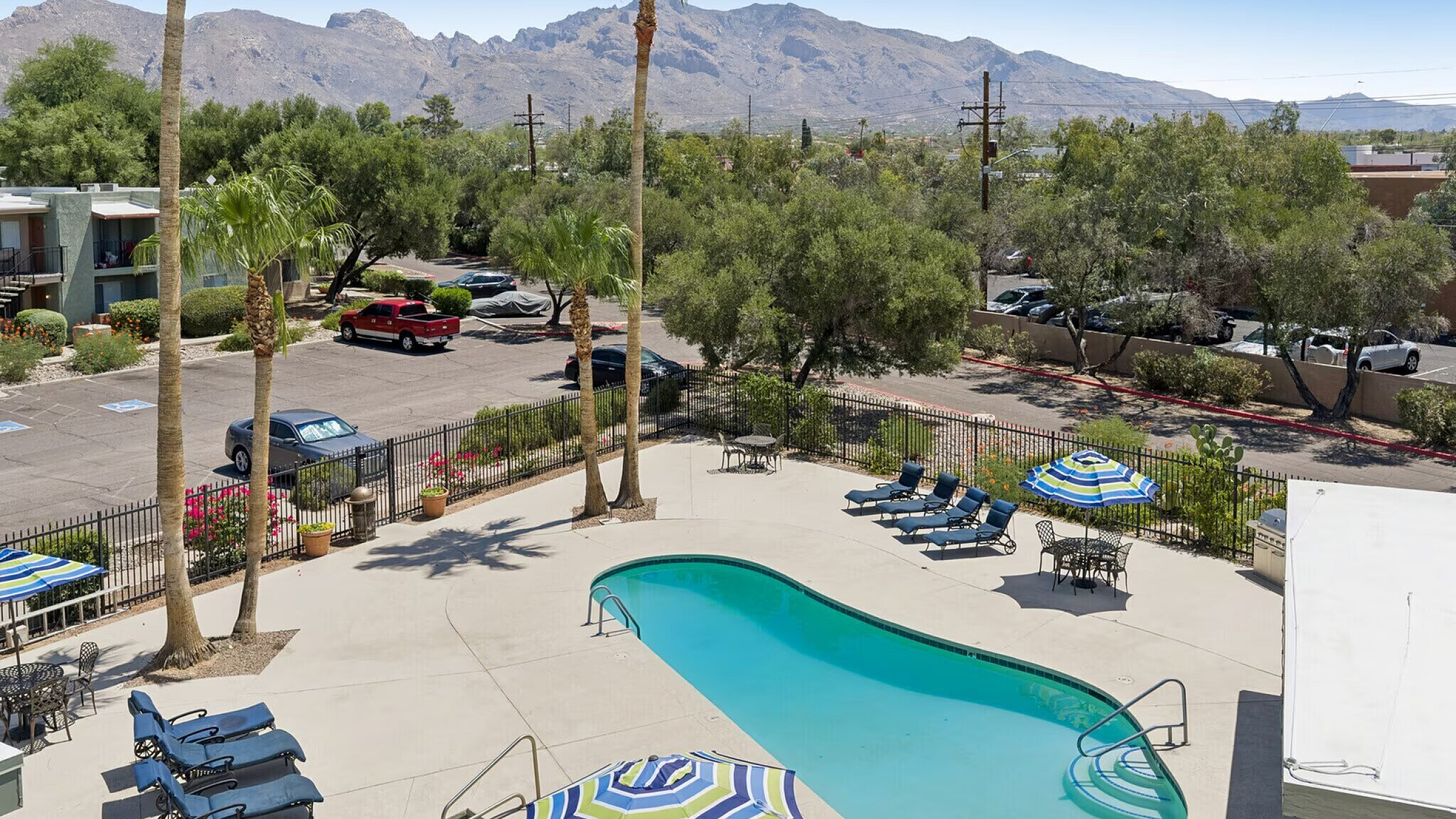 Inviting apartment community pool with lounge chairs, vibrant umbrellas, and stunning mountain views. in Mountain Village