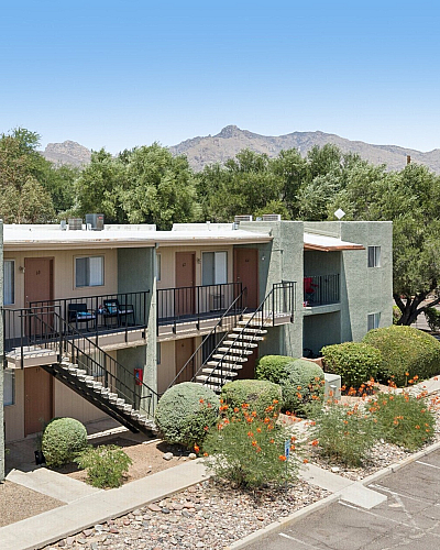 Charming apartment complex with mountain views, lush greenery, and vibrant landscaping, promising serene living.