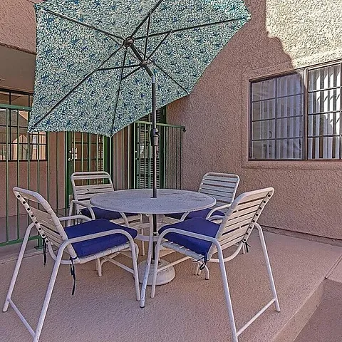 Inviting outdoor patio with stylish furniture and a floral umbrella, perfect for relaxing and entertaining.