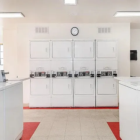 Bright and spacious laundry room featuring modern washers and dryers, complemented by large windows for natural light.