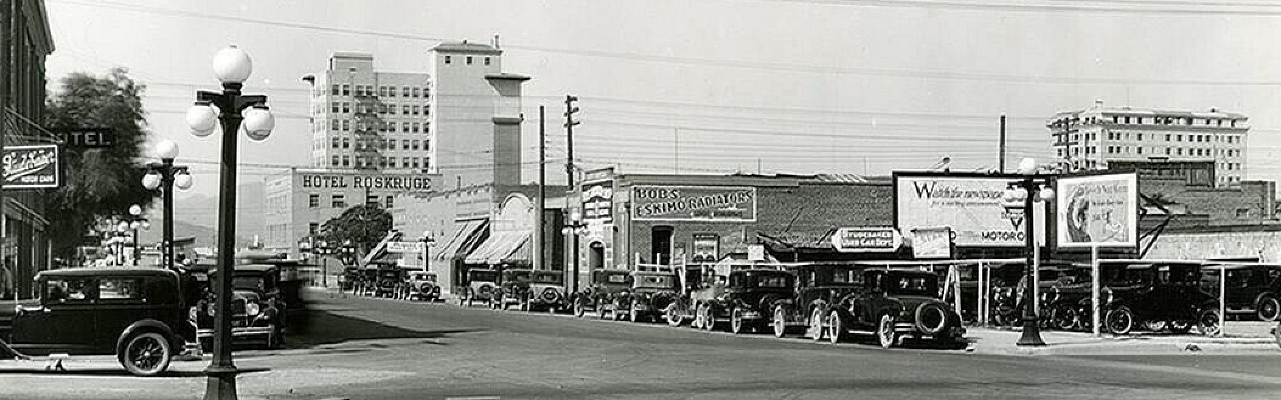 Charming vintage city street scene with classic cars and historic buildings, including the iconic Hotel Roskruge, capturing a timeless urban vibe.