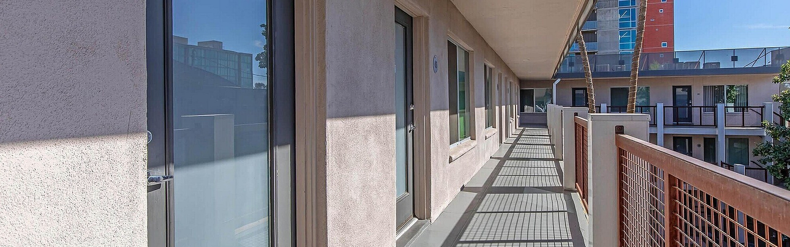 Modern apartment corridor with sleek architecture, featuring large glass doors and an outdoor balcony space.