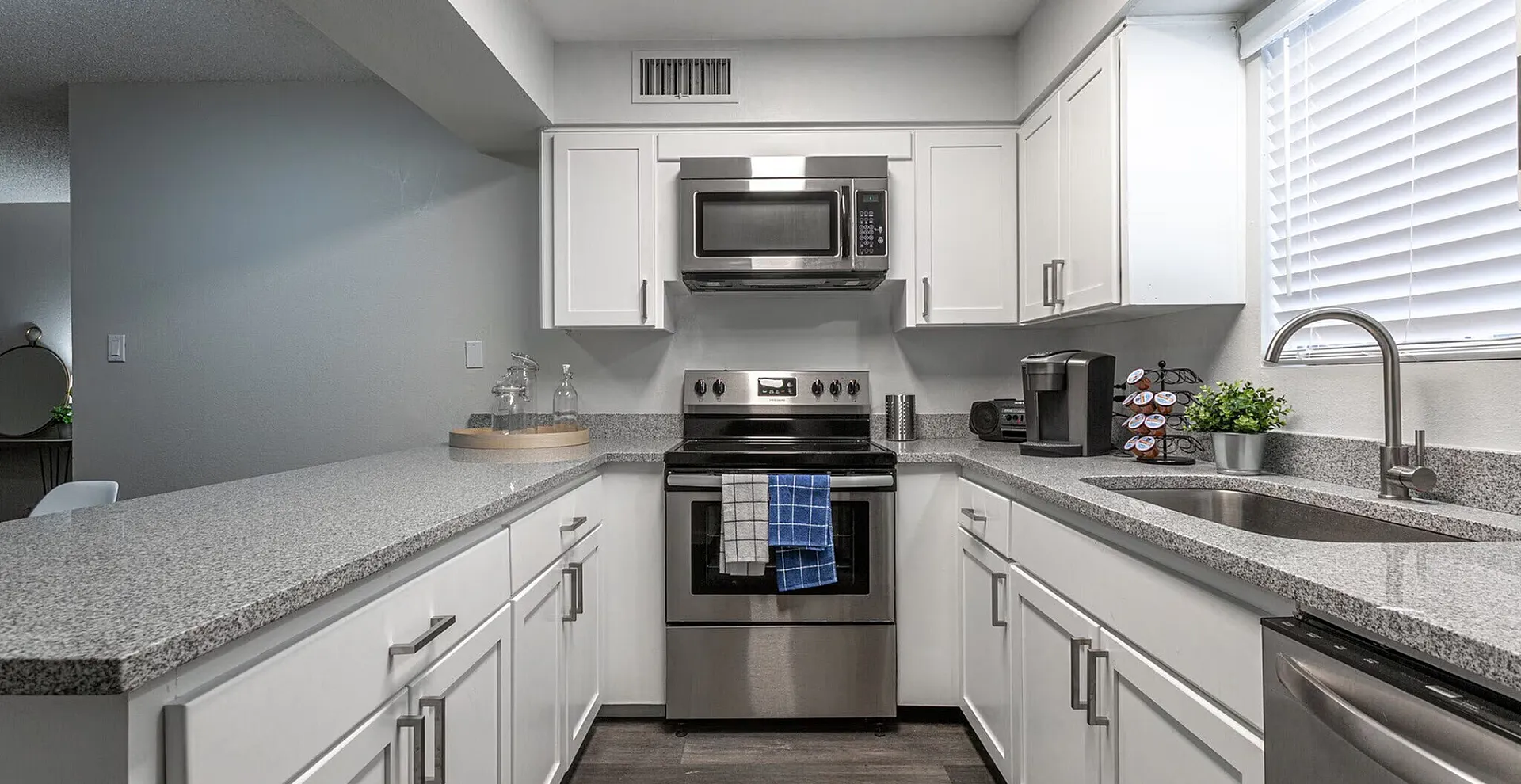 Contemporary kitchen with sleek granite countertops, modern appliances, and stylish white cabinetry, perfect for culinary enthusiasts.