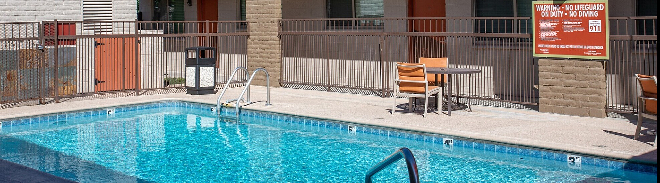 Vibrant apartment complex with a sparkling pool surrounded by modern architecture, offering a serene outdoor space.