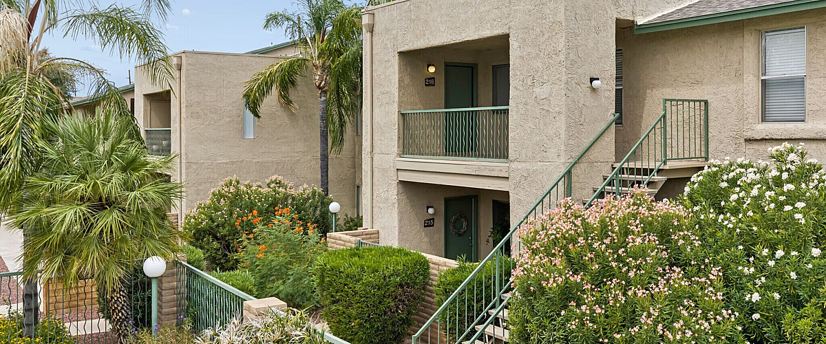 Charming apartment exterior with lush tropical landscaping and welcoming entryway, showcasing California living.