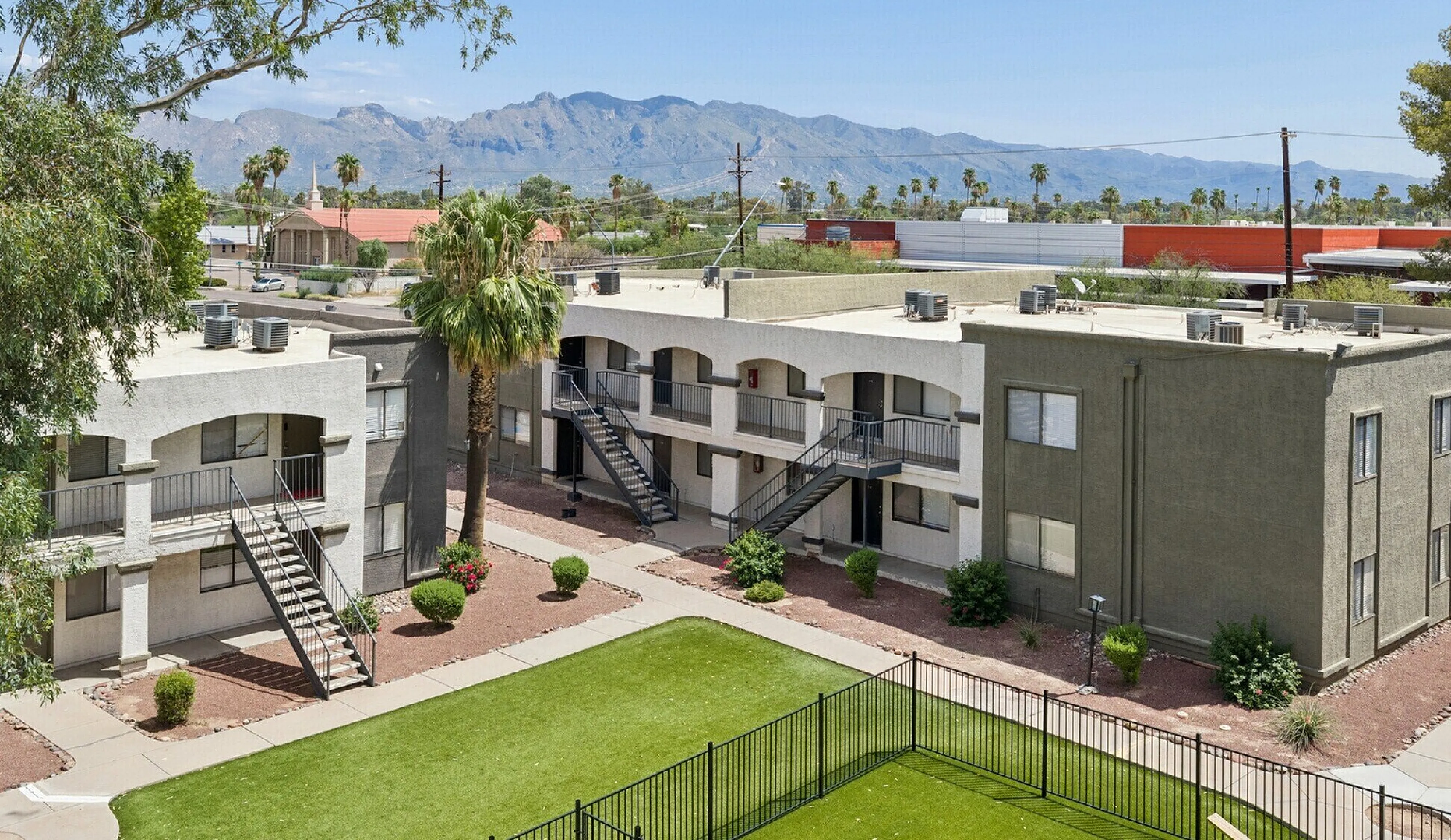 Charming apartment complex with mountain views, featuring modern two-story buildings, lush greenery, and a spacious courtyard.