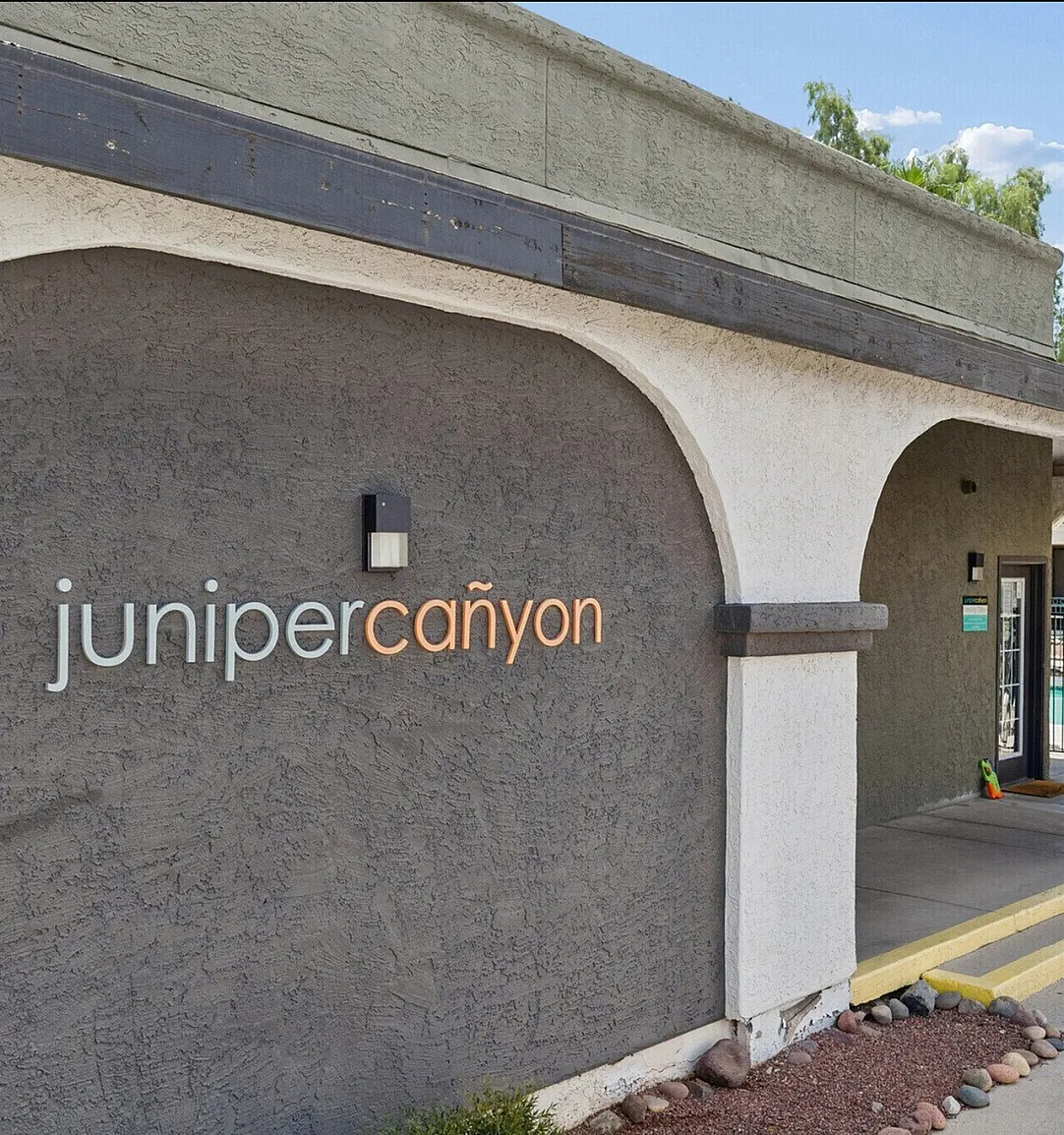 Inviting entrance of Juniper Canyon apartments featuring elegant archways and lush greenery.