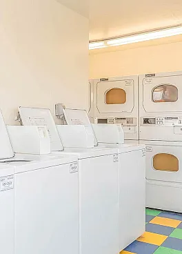Contemporary laundry room featuring multiple efficient washers and dryers with vibrant checkered flooring.