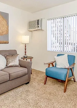 Bright and cozy living space featuring a stylish sofa, modern artwork, and a comfortable armchair with natural light streaming through the window.