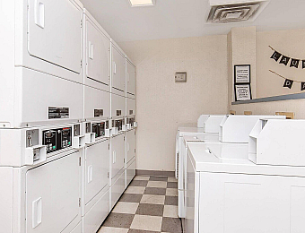 Bright and convenient laundry room featuring multiple modern washers and dryers, perfect for easy living.