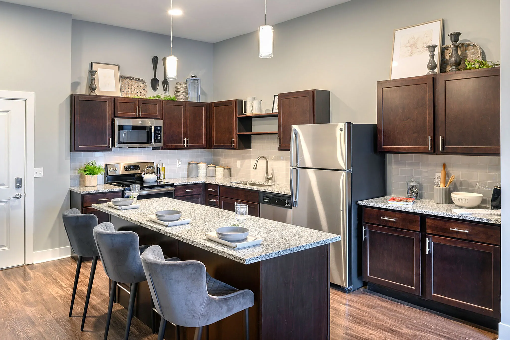 Modern kitchen with sleek stainless steel appliances, elegant granite countertops, and stylish dark wood cabinetry. Features an inviting island with comfortable seating, perfect for social gatherings.
